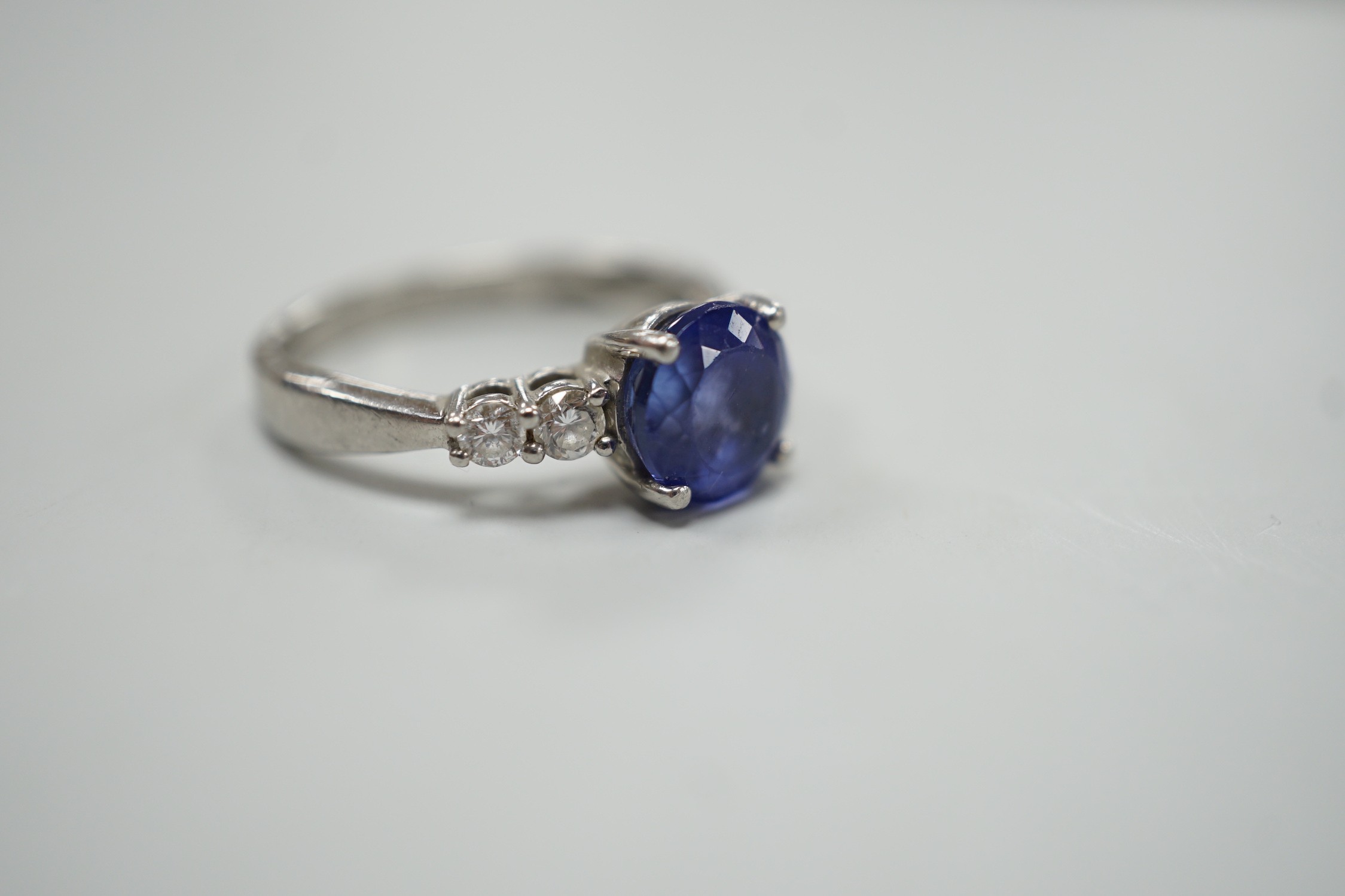 A modern Illiana platinum, single stone round cut tanzanite and four stone diamond set dress ring, size O, gross weight 5.7 grams.